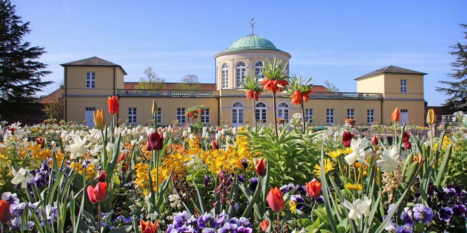 Historisches Geb&auml;ude mit Sommerblumenbeeten im Vordergrund