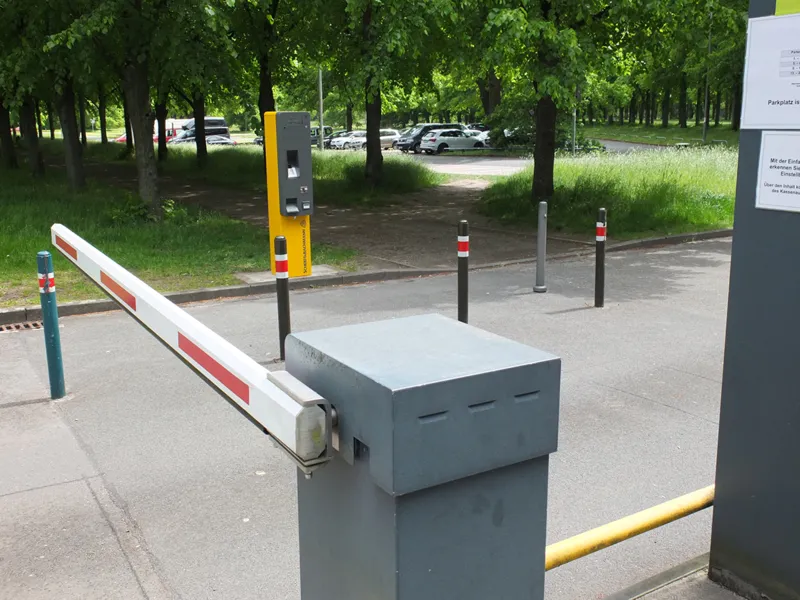 Kartenautomat und geschlossene rotwei&szlig;e Schranke am Parkplatz
