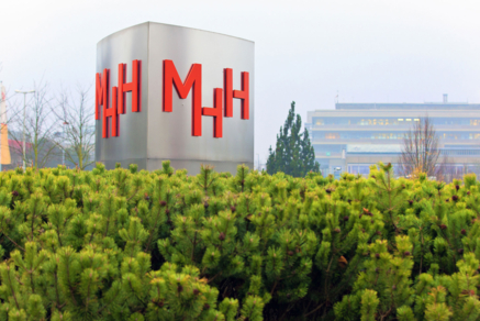 Eine Säule mit den Buchstaben "MHH", im Hintergrund Gebäude.